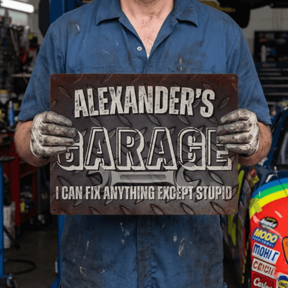 Metal Garage Sign with personalized name and humorous quote about fixing things, set in a mechanic's workshop.